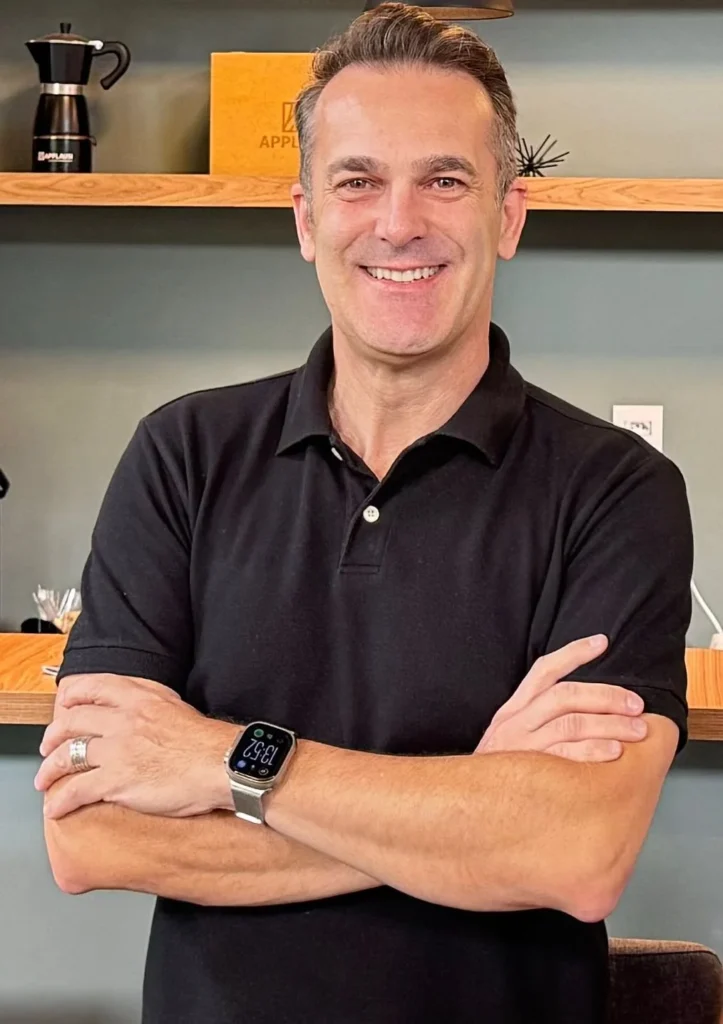 Marcos Soares, fundador da Update Imobi, sorrindo de braços cruzados